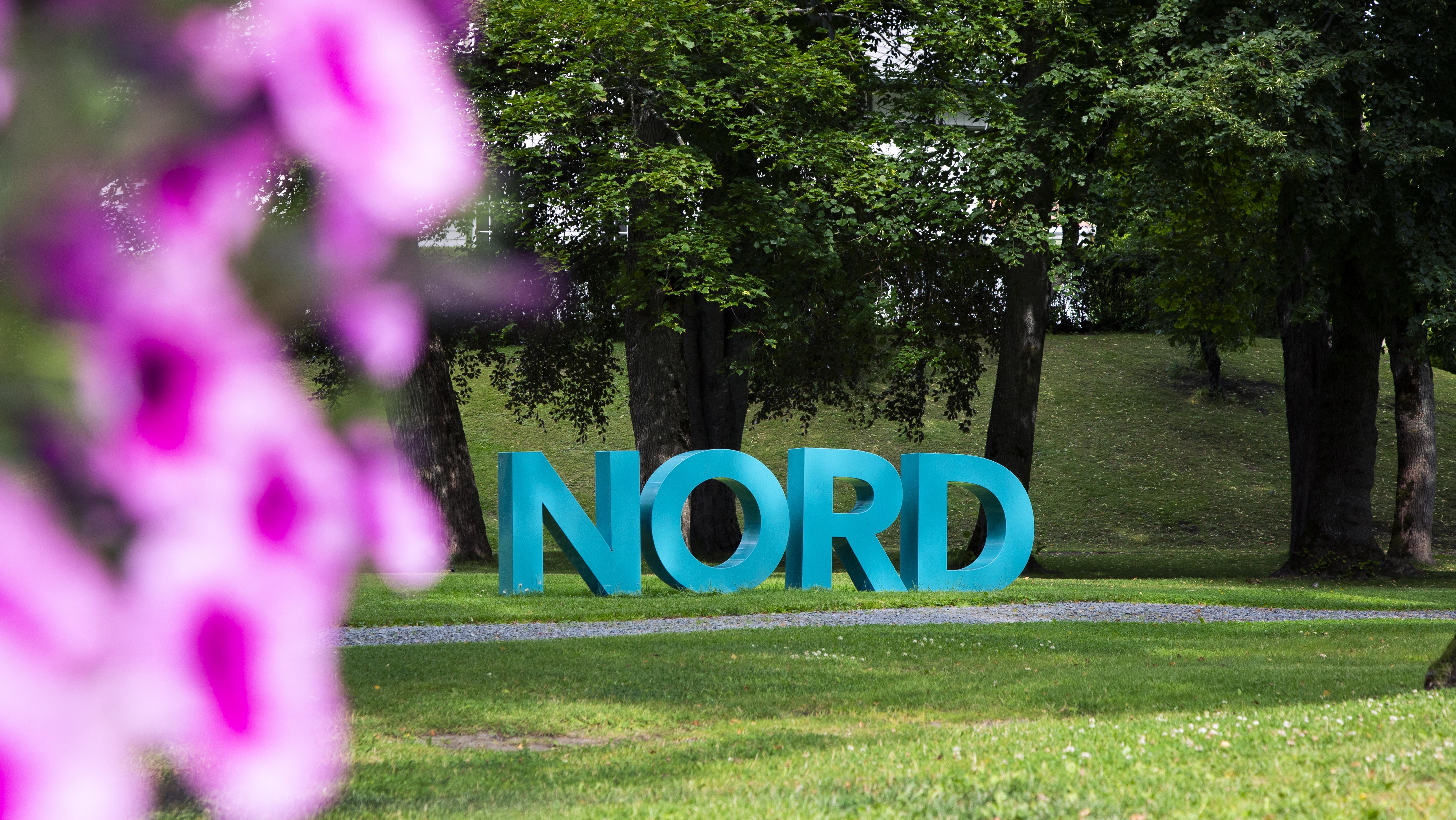 Nord universitet-bokstaver med blomster i forgrunnen