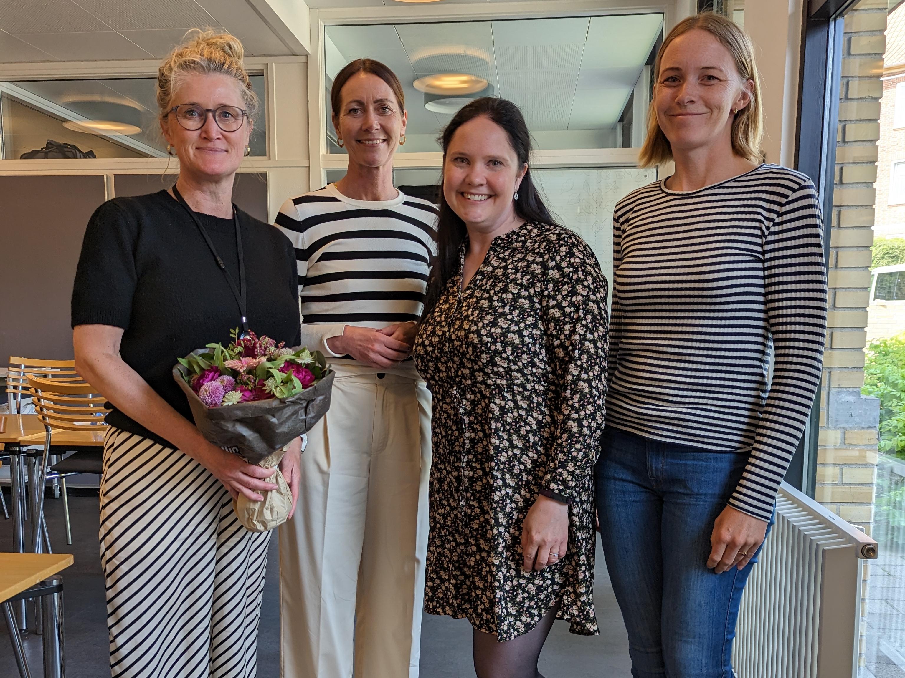 Fire kvinner side om side i et rom ved et vindu.