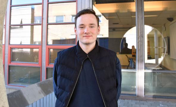 Student står utenfor inngangsdøra til campus.