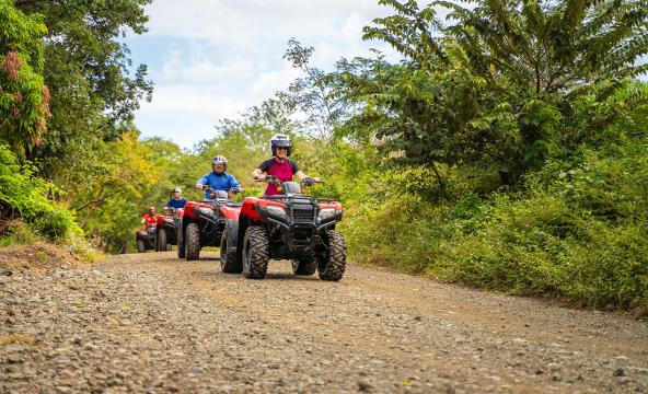 Fire ATV-er som kjører i kø på en grusveg. Foto