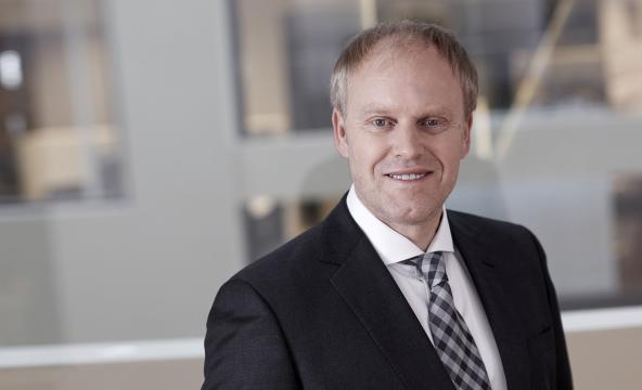 Portrettbilde av voksen mann i dressjakke, skjorte og med slips. Foto