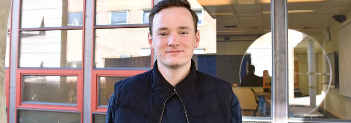 Student står utenfor inngangsdøra til campus.