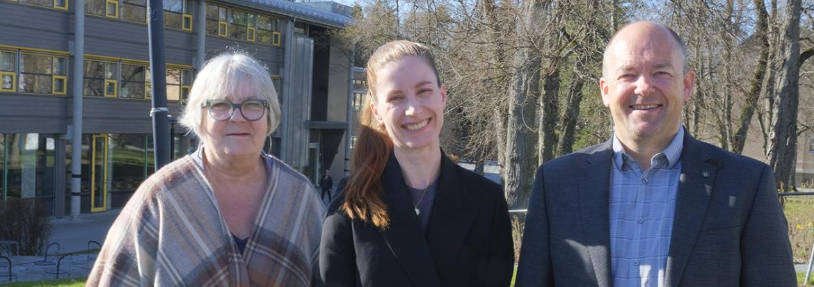 Prodekan forskning, dekan og prosjektleder står foran en av bygningene på campus Levanger.