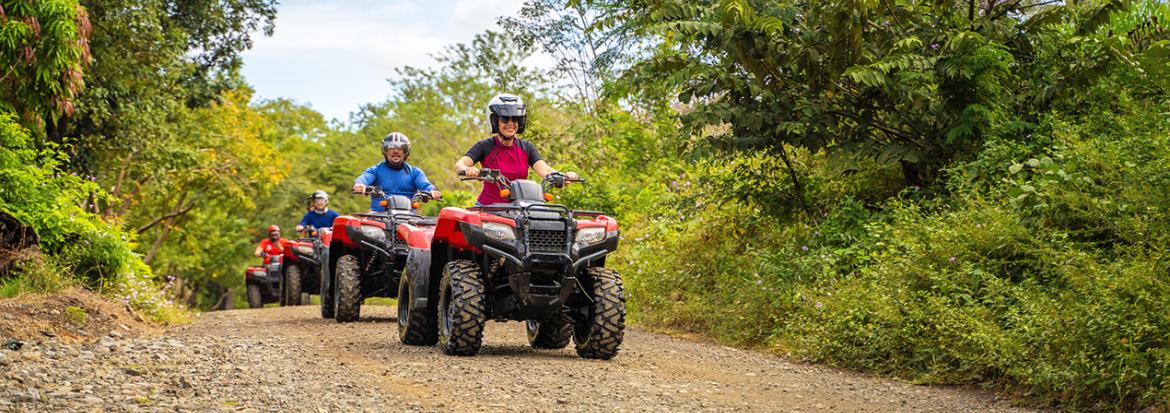 Fire ATV-er som kjører i kø på en grusveg. Foto