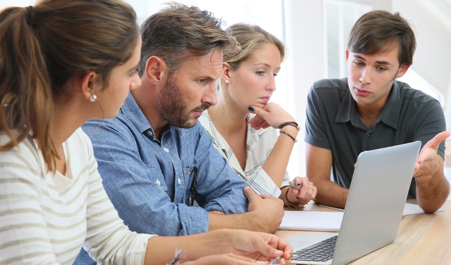 Fire personer arbeider ved en PC.