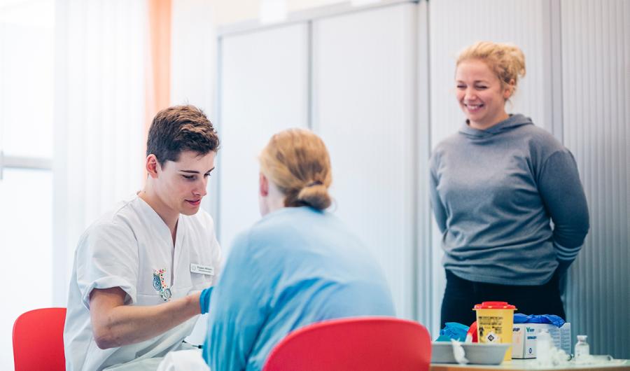 Tre sykepleiestudenter som øver. Foto