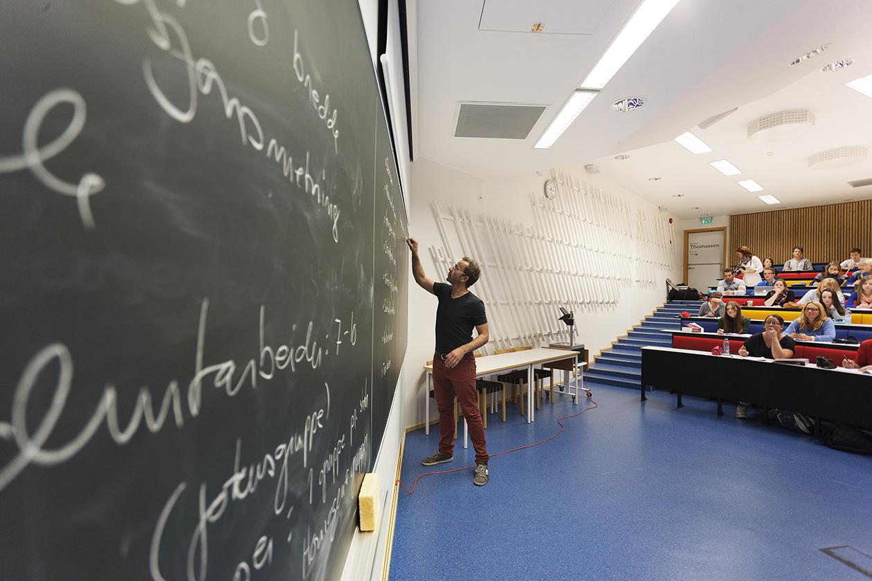 Foreleser og studenter i et auditorium.