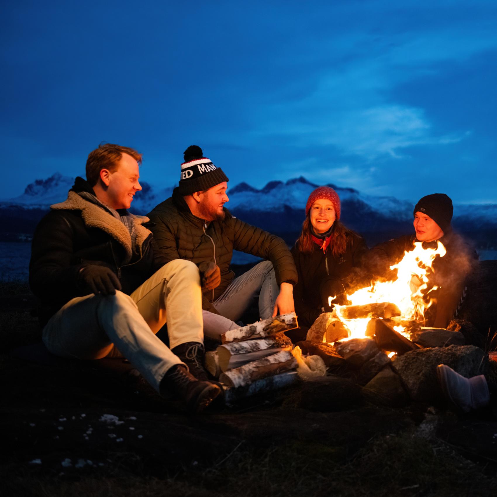 Studenter som sitter rundt et bål en høstkveld