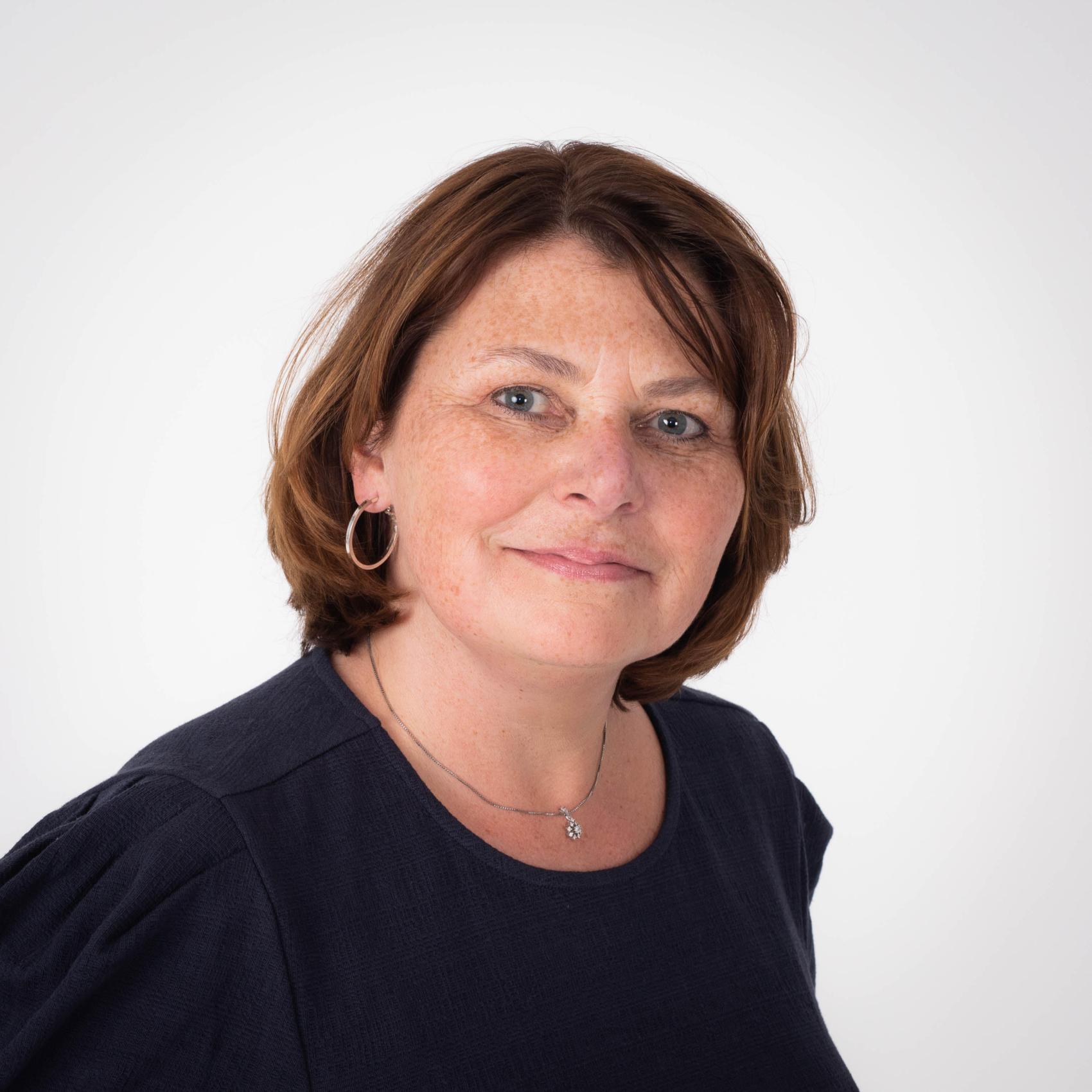 Portrett av dame, med hvit vegg i bakgrunnen. Foto.