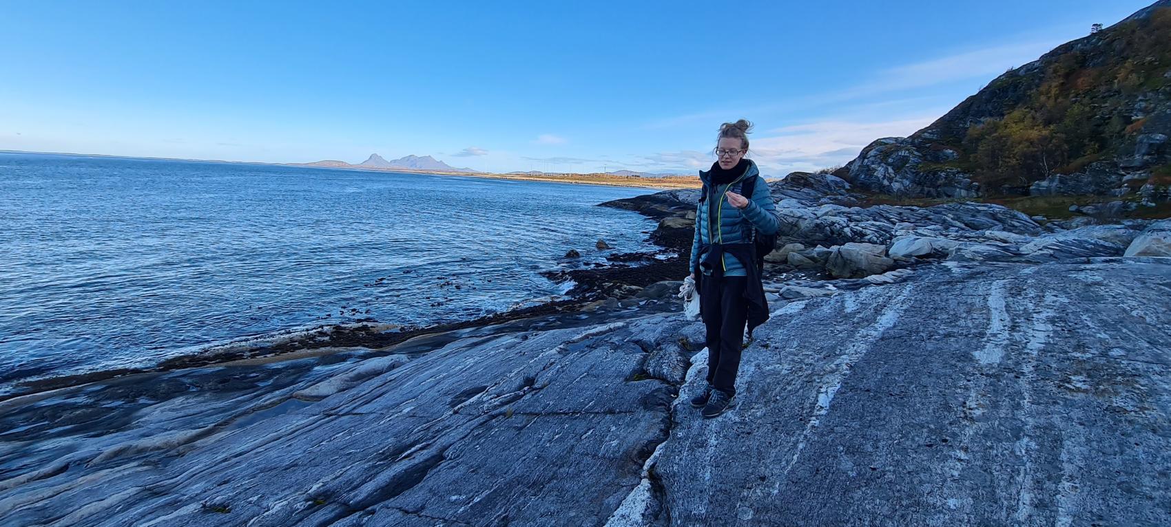 Kvinne går på berget ved havet