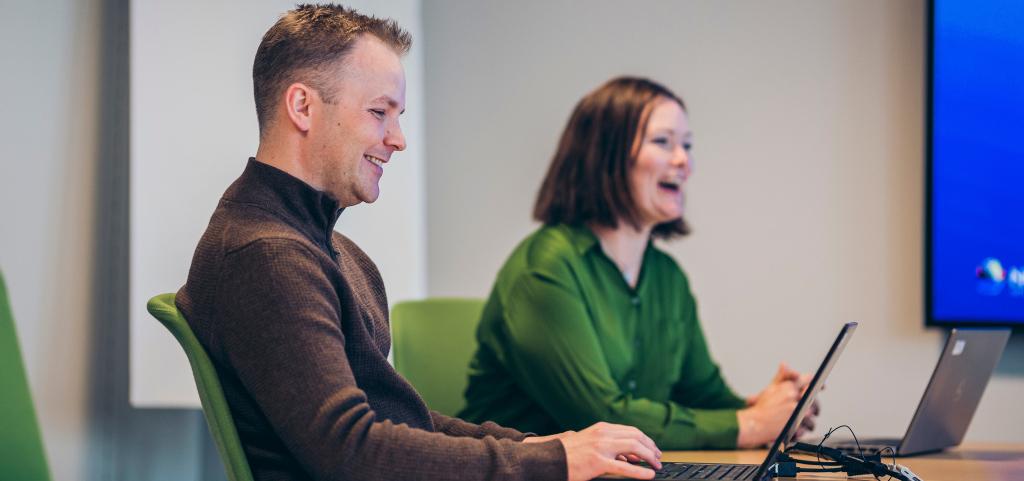 To personer på kontor som ler og smiler