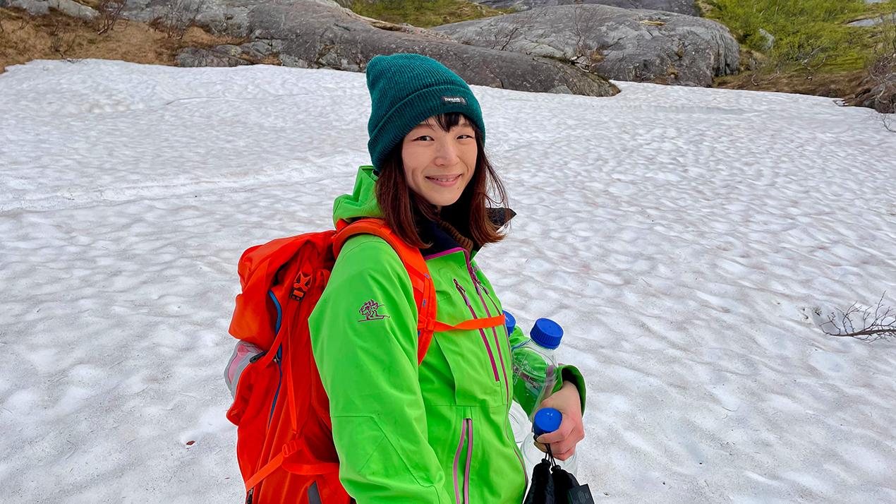 Kvinnelig forsker med lue og sekk på isen. Foto