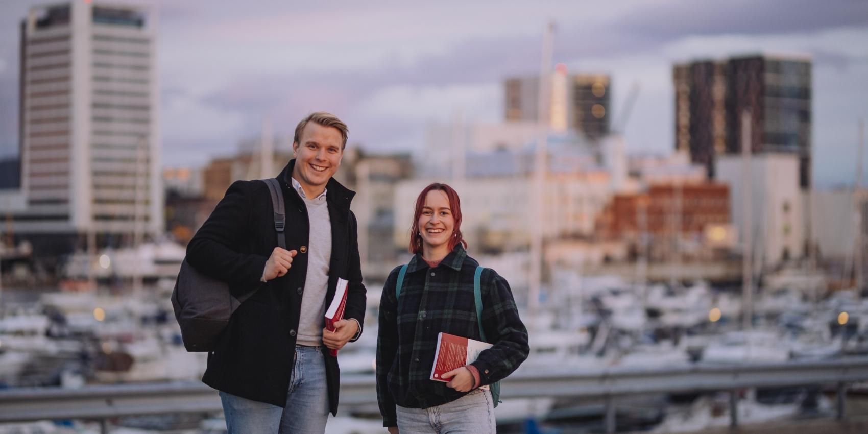 To studenter som smiler, med Bodø by i bakgrunnen.