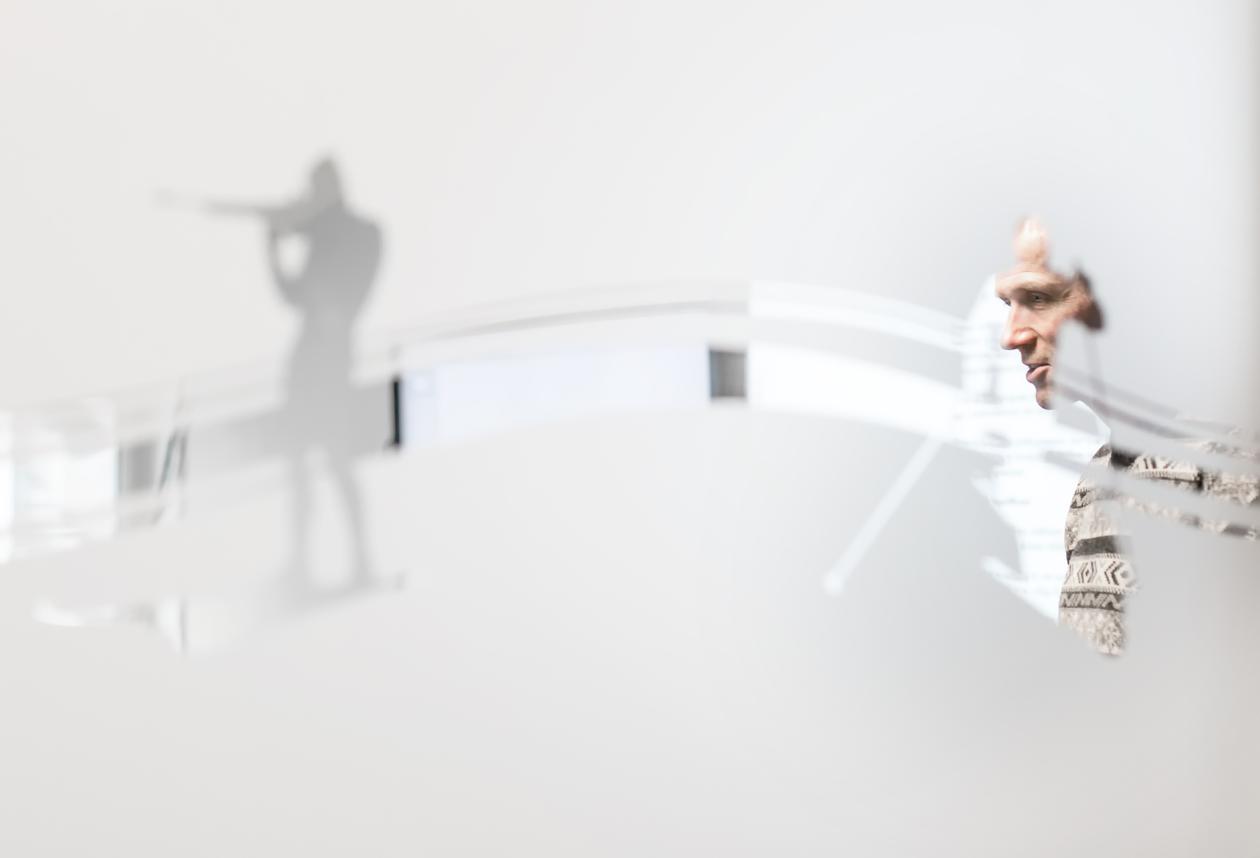 Deler av en voksen mann som ses gjennom et mønster i et vindu. Foto