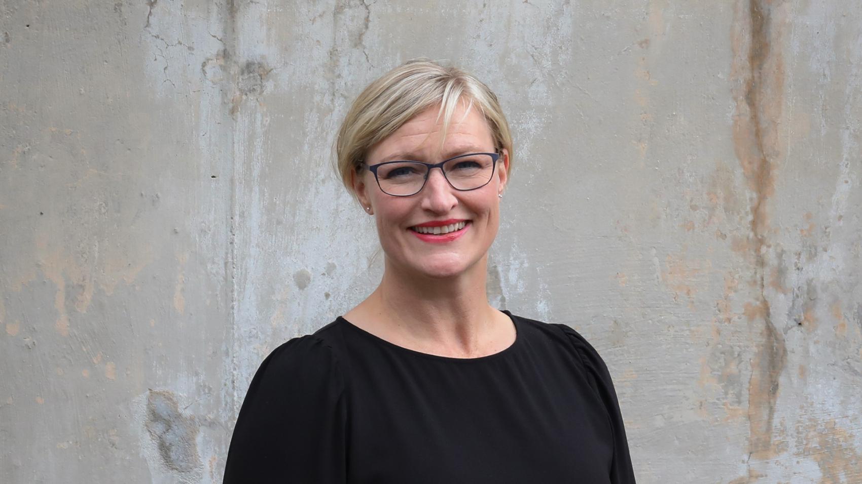Portrettbilde av Ann Karin Orset foran murvegg