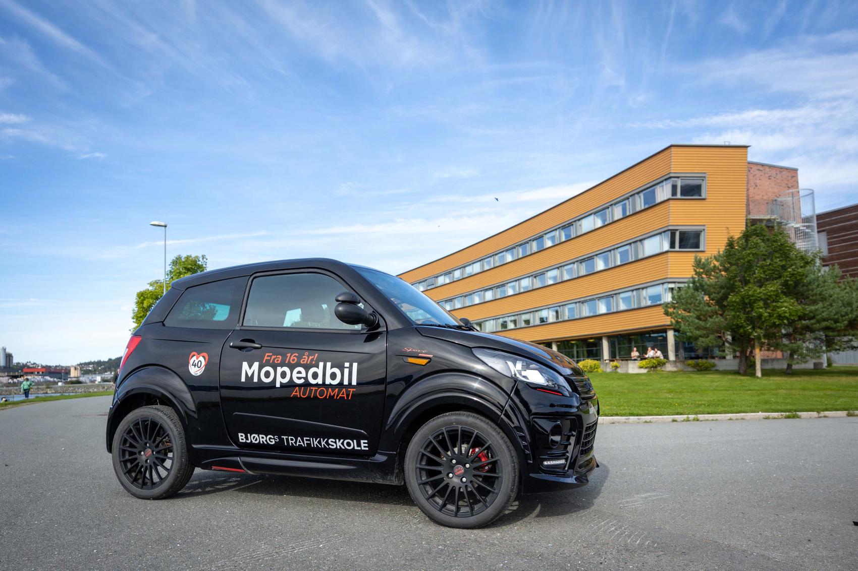 Mopedbil parkert ute under blå himmel