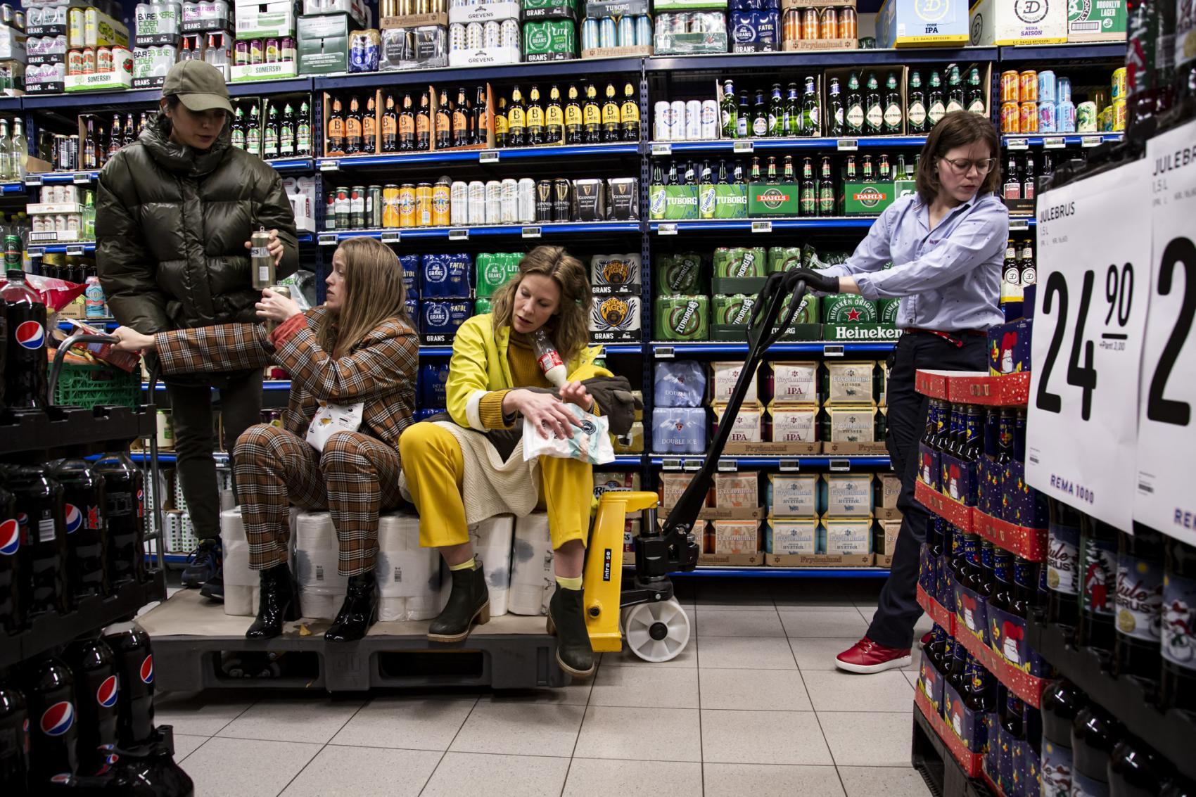 Bilde fra en teaterforestilling, med fire personer inne i en trang butikk mellom reoler og varer. Foto