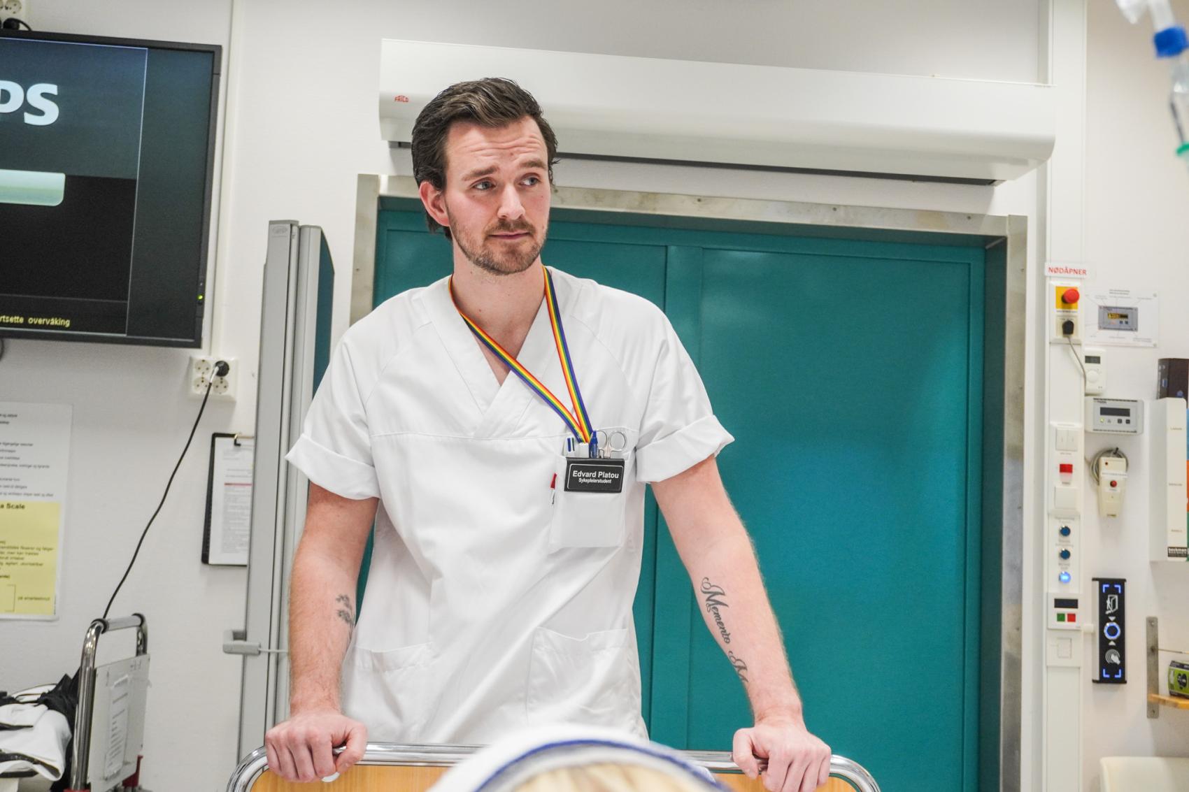 Mannlig sykepleierstudent som holder i ei sykeseng. Foto