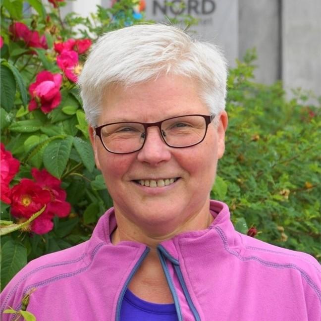 Dame som smiler inn i kamera. 