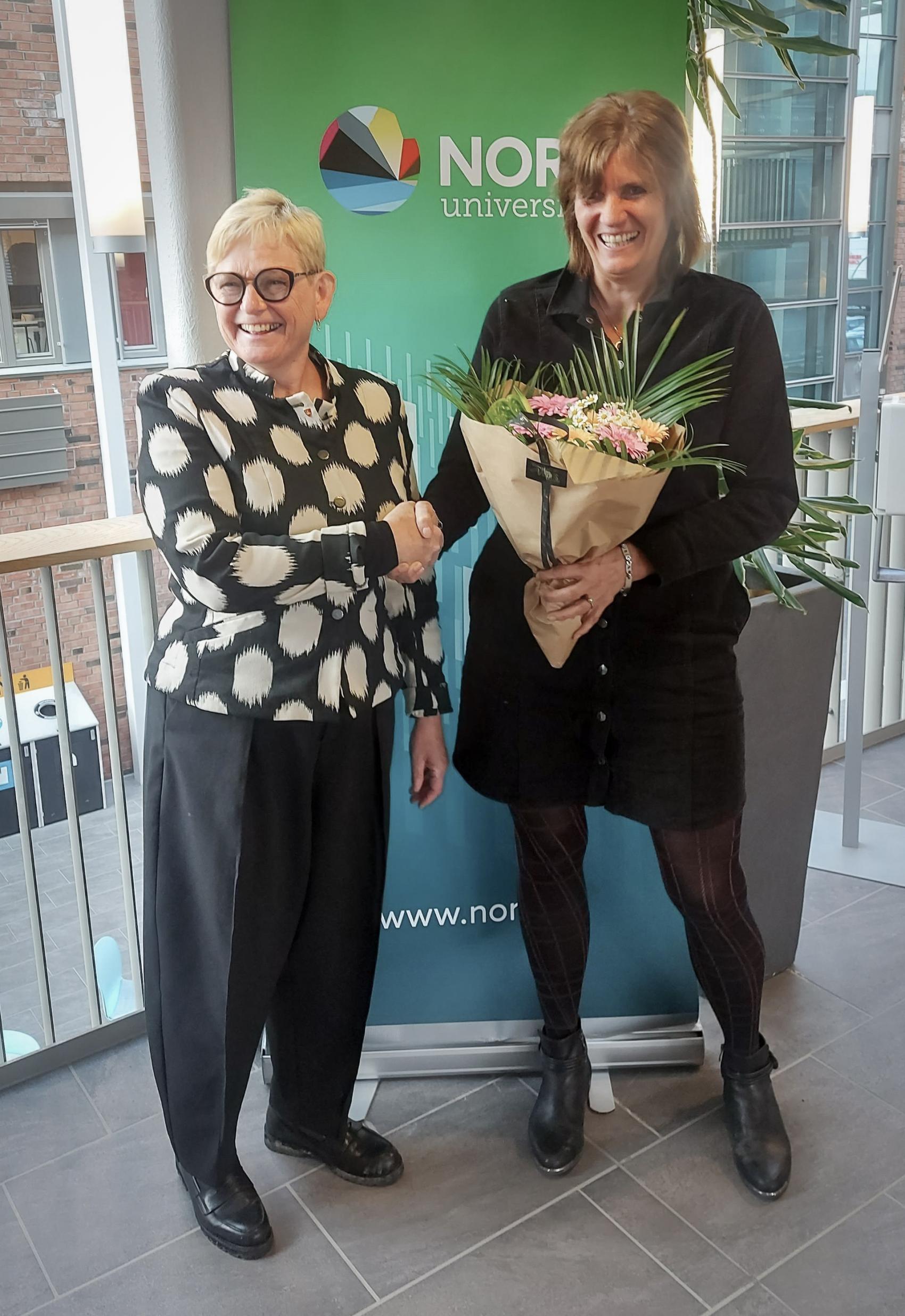 Kvinnelig ordfører overrekker blomster til annen kvinne