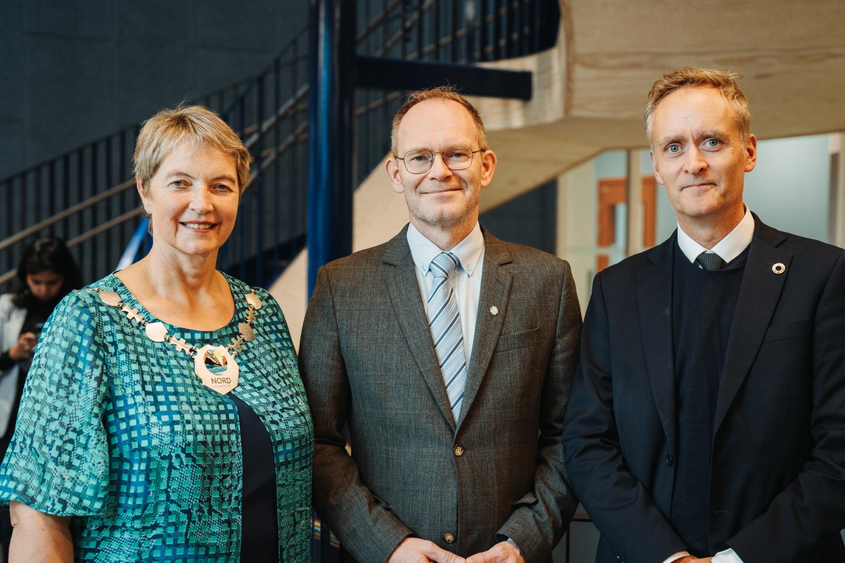 En kvinne og to menn i pene klær under åpning av nytt bygg. Foto