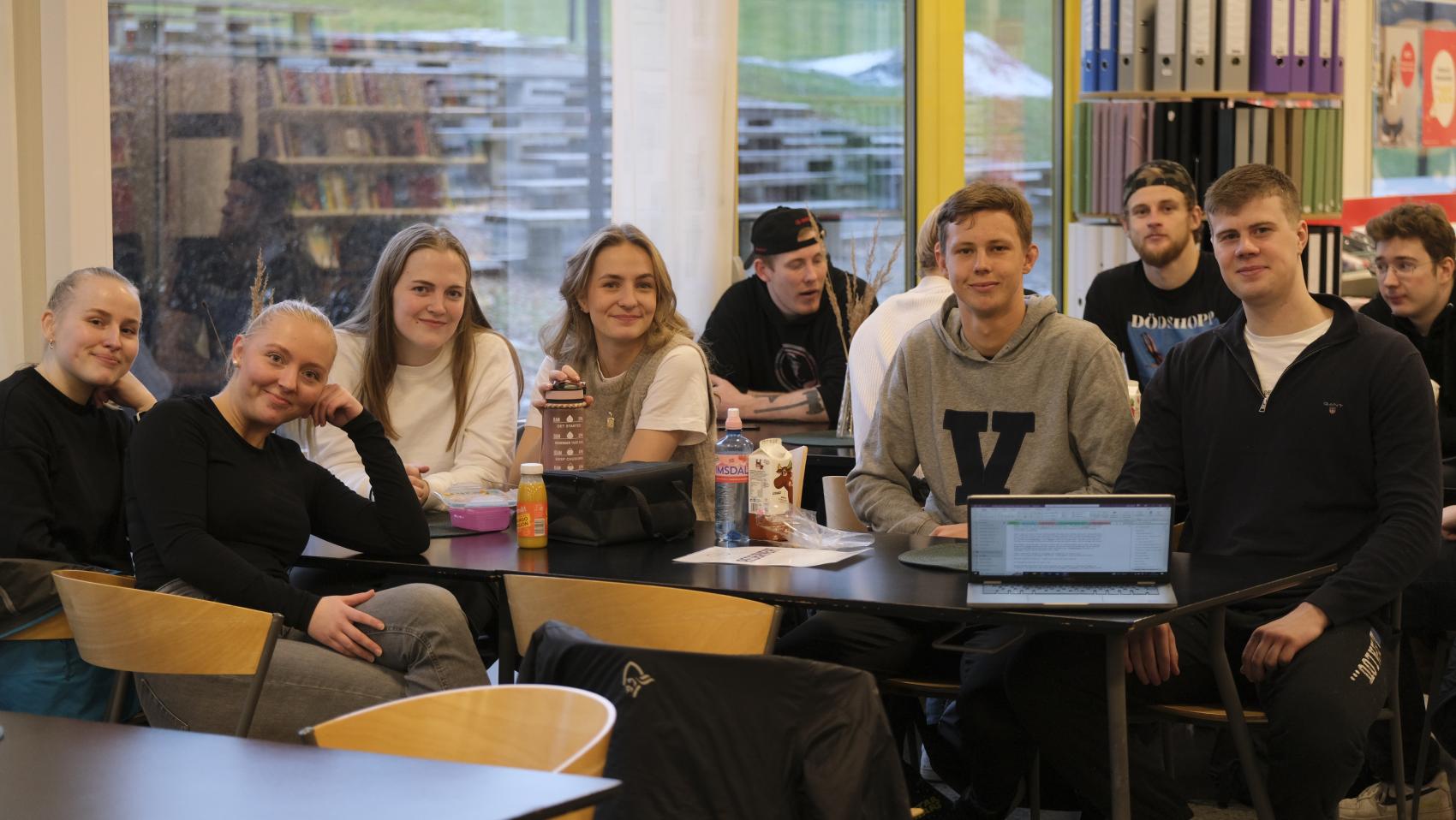 Ti studenter rundt et bord i en kantine. Foto