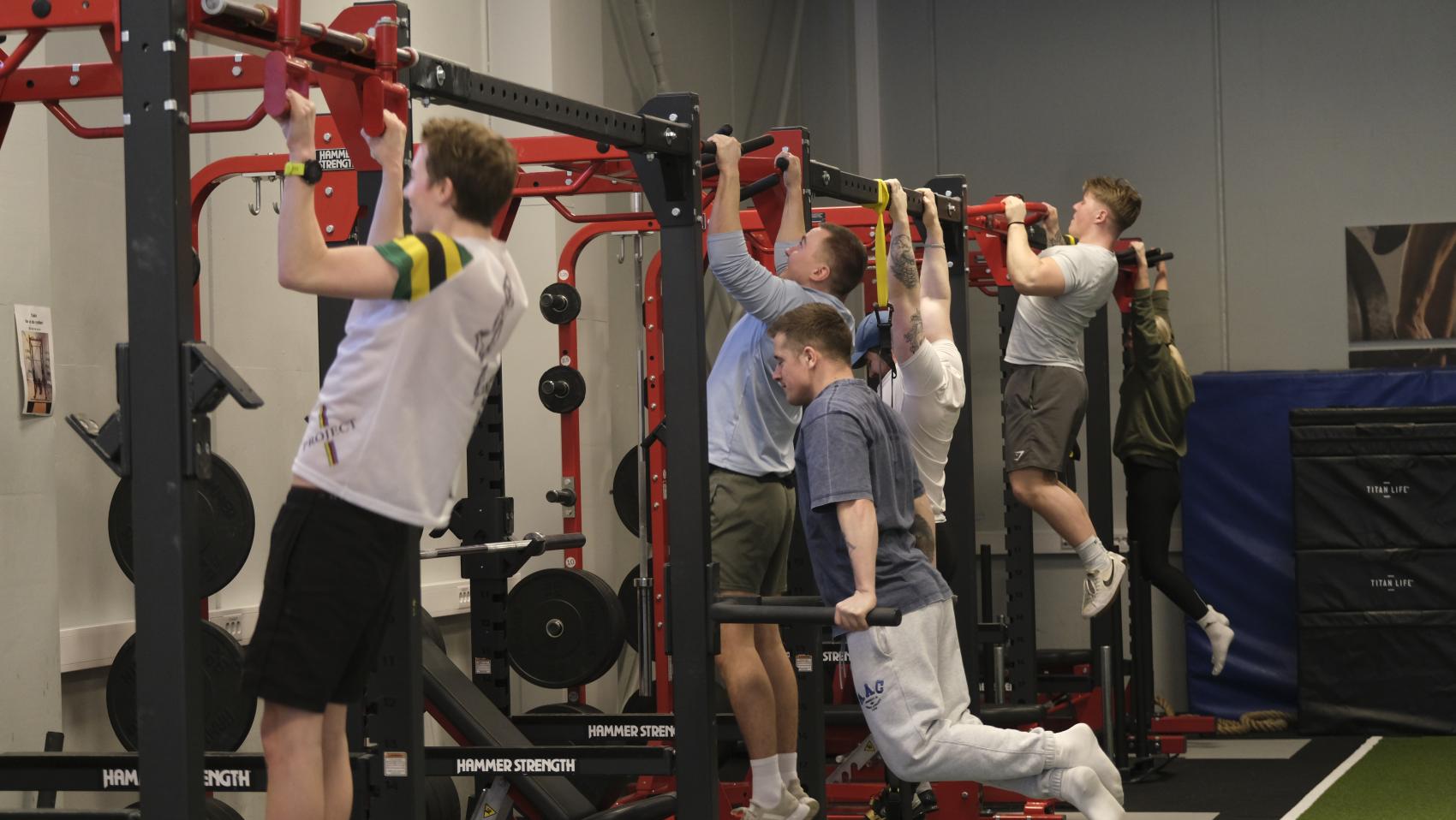 Fem unge menn som trener styrke. Foto